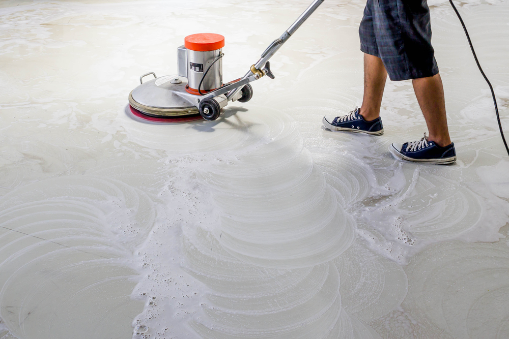 Worker using scrubber machine for tile cleaning